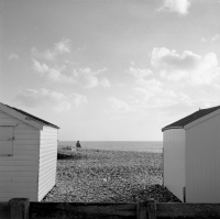 person on beach between beach huts